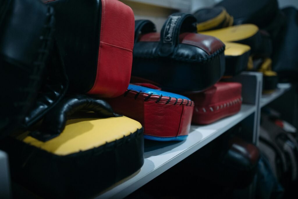 Boxing gloves and focus pads stacked on a gym shelf