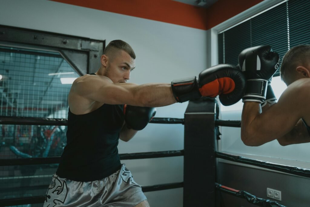 Boxer wearing black gloves during pad training in a boxing ring