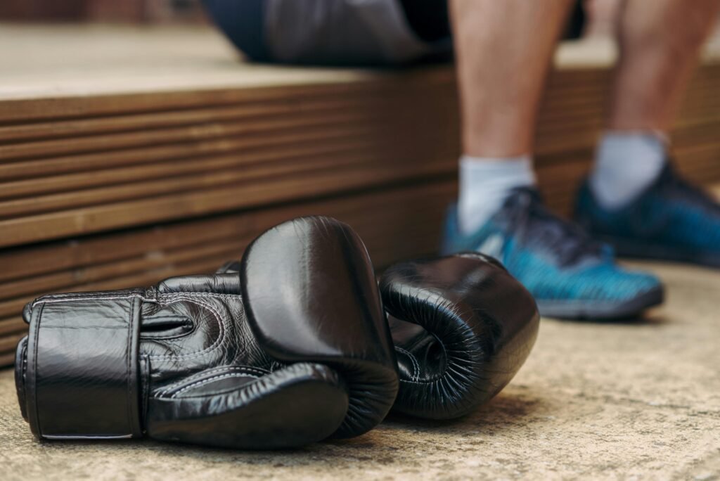 Pair of black leather boxing gloves resting on a gym bench