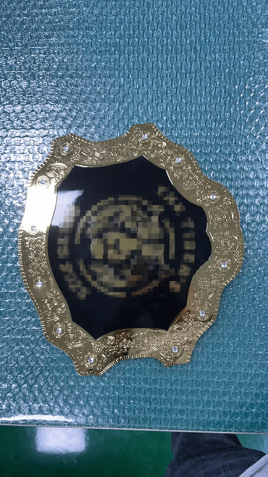 Close-up of a finished custom championship belt plate during pre-shipment visual review